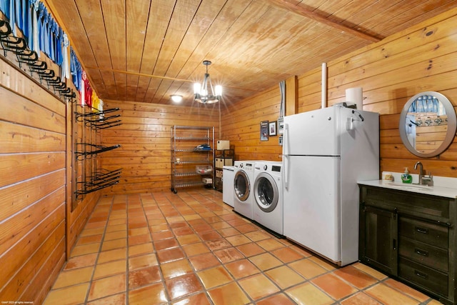 washroom featuring wood walls, an inviting chandelier, light tile patterned floors, wood ceiling, and washing machine and clothes dryer