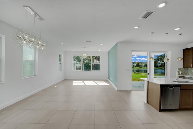 kitchen with light tile patterned flooring, stainless steel dishwasher, hanging light fixtures, and sink