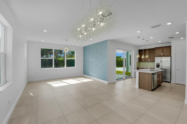 kitchen with a center island with sink, hanging light fixtures, plenty of natural light, and appliances with stainless steel finishes