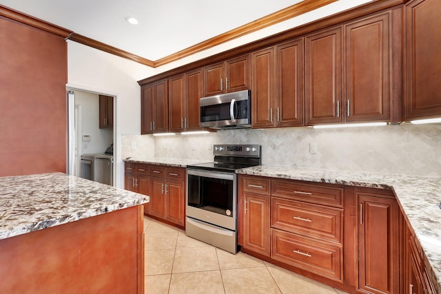 kitchen featuring crown molding, vaulted ceiling, independent washer and dryer, appliances with stainless steel finishes, and light stone counters