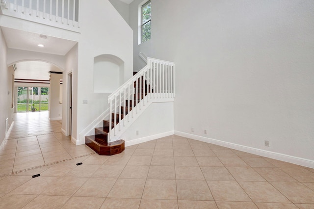 stairway with tile patterned floors, a healthy amount of sunlight, and a high ceiling