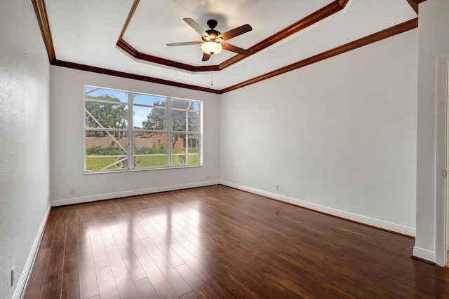 empty room featuring a raised ceiling, dark hardwood / wood-style floors, ceiling fan, ornamental molding, and a textured ceiling