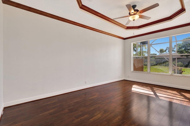 empty room with a tray ceiling, ceiling fan, dark hardwood / wood-style flooring, and ornamental molding