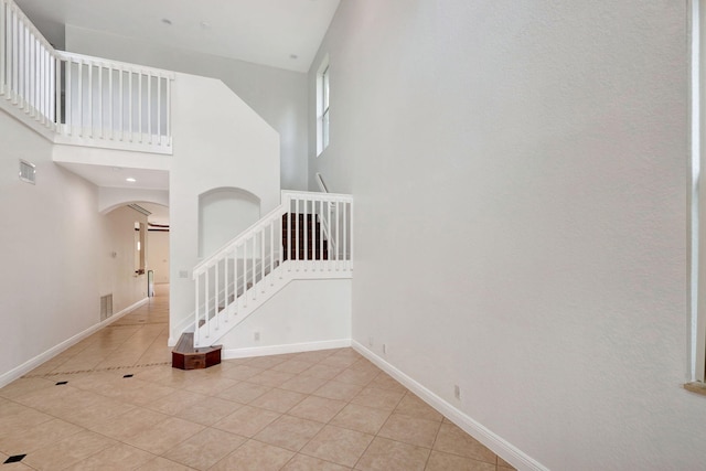 stairway featuring tile patterned flooring and a high ceiling