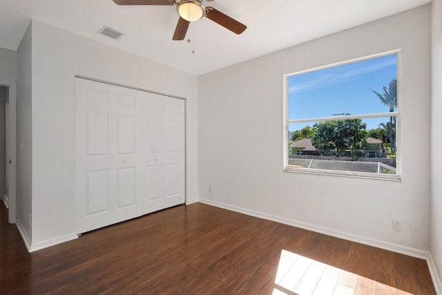 unfurnished bedroom with ceiling fan, a closet, and dark hardwood / wood-style floors