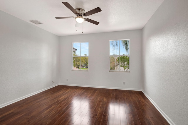 empty room with ceiling fan and dark hardwood / wood-style flooring