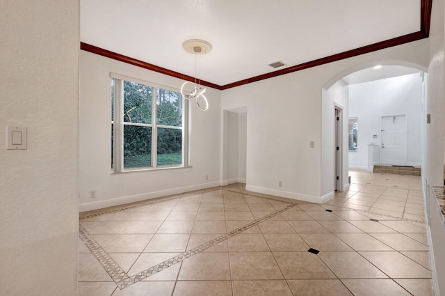 tiled spare room with ornamental molding and a chandelier