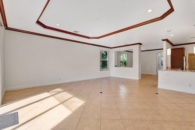 unfurnished living room with a tray ceiling, crown molding, and light tile patterned flooring