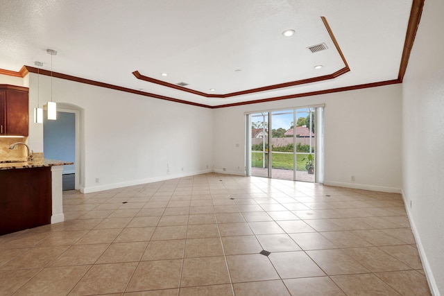 tiled spare room with a raised ceiling, ornamental molding, and sink