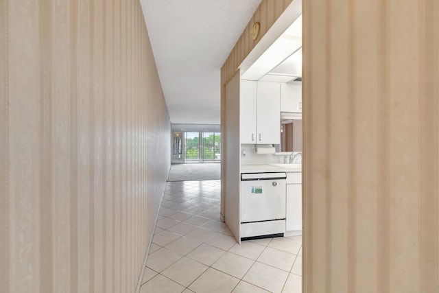 kitchen with dishwasher, white cabinetry, sink, and light tile patterned floors