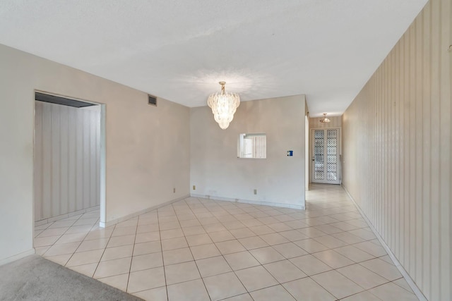 unfurnished room featuring a notable chandelier and light tile patterned flooring