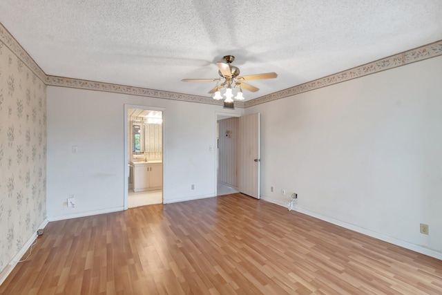 unfurnished bedroom featuring a textured ceiling, ensuite bath, light hardwood / wood-style flooring, and ceiling fan