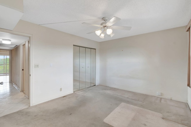 unfurnished bedroom featuring ceiling fan, light colored carpet, and a textured ceiling