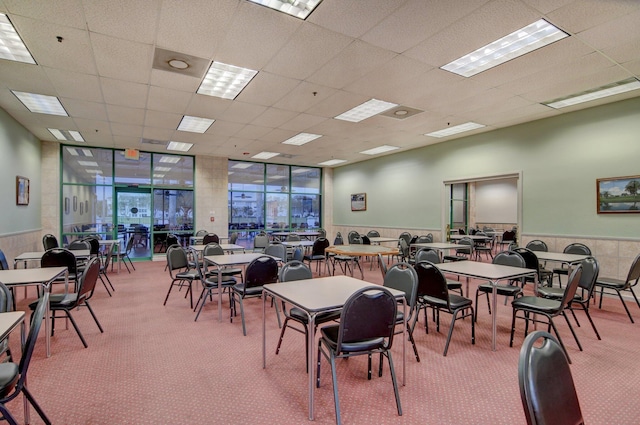 dining space with carpet, a paneled ceiling, and expansive windows