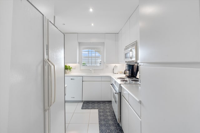 kitchen featuring light tile patterned floors, white appliances, white cabinetry, and sink