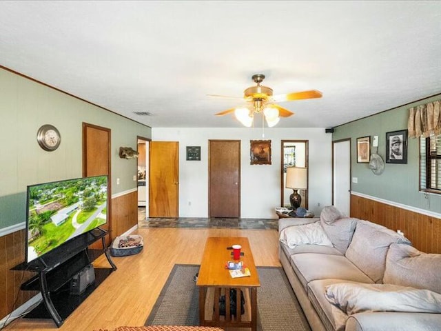 living room with ceiling fan, hardwood / wood-style floors, and wooden walls