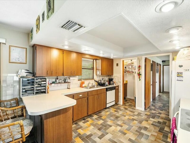 kitchen featuring sink, white appliances, kitchen peninsula, and a textured ceiling