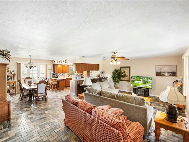 living room featuring a textured ceiling and ceiling fan with notable chandelier