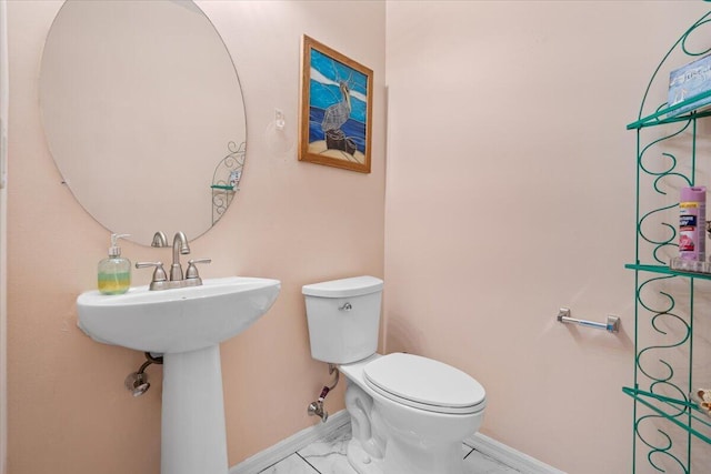 bathroom with toilet, baseboards, and marble finish floor