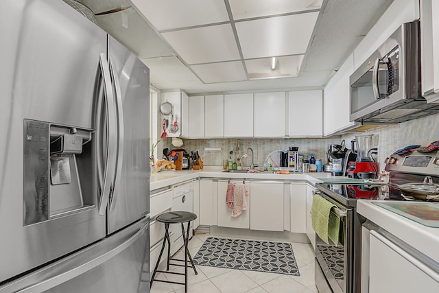 kitchen featuring sink, stainless steel appliances, light tile patterned floors, decorative backsplash, and white cabinets