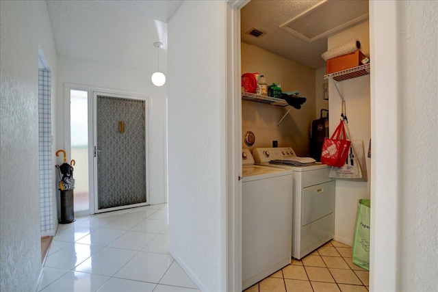 laundry room featuring washer and dryer, light tile patterned floors, a textured ceiling, and water heater