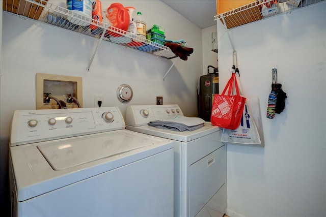 washroom featuring a textured ceiling, separate washer and dryer, and water heater