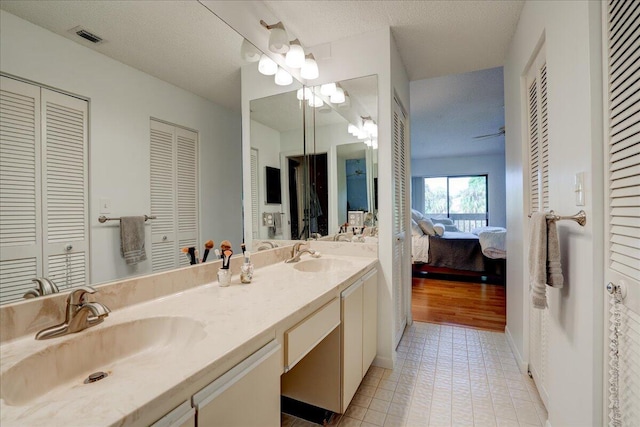 bathroom with tile patterned flooring, vanity, and a textured ceiling