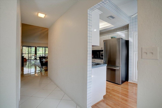 hallway with a textured ceiling and light wood-type flooring