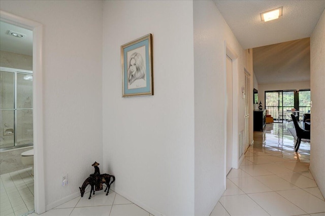 corridor with a textured ceiling and light tile patterned flooring