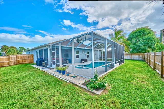 rear view of house with glass enclosure, a fenced in pool, and a yard