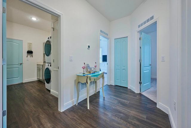 corridor with dark hardwood / wood-style floors and stacked washer / dryer