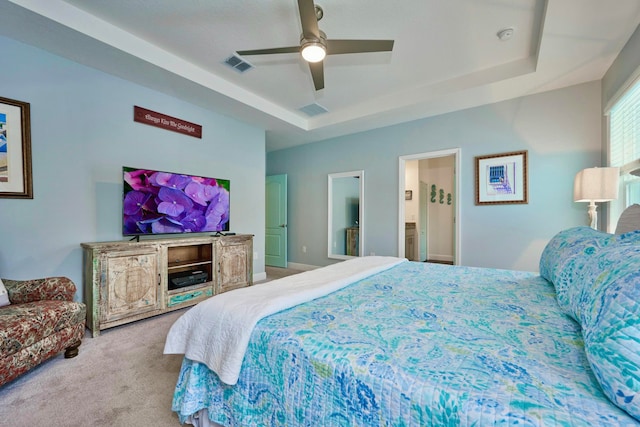 bedroom with carpet floors, ensuite bathroom, ceiling fan, and a tray ceiling