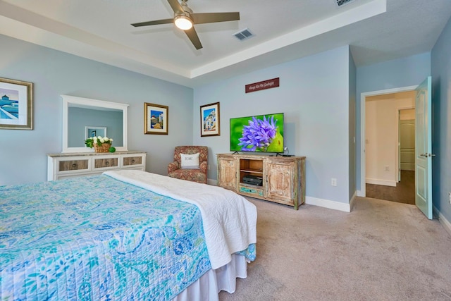 carpeted bedroom featuring ceiling fan and a tray ceiling