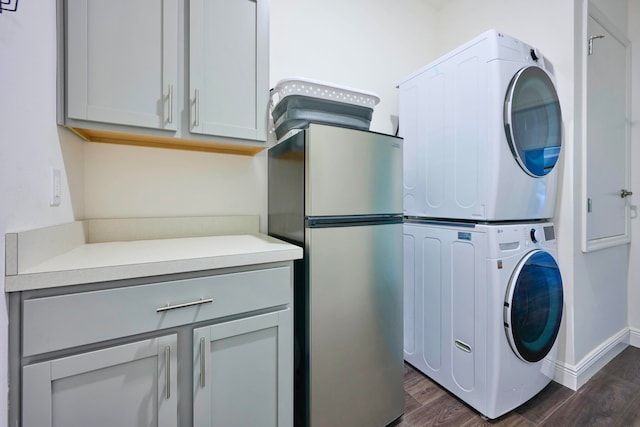 washroom with cabinets, stacked washing maching and dryer, and dark wood-type flooring