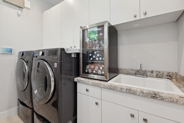 clothes washing area with washer and clothes dryer, light tile patterned floors, cabinets, and sink