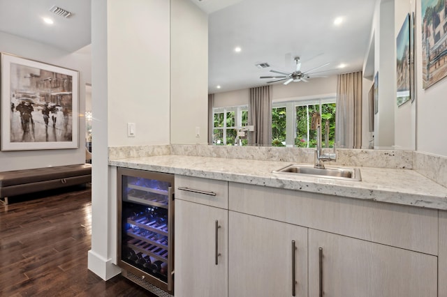 kitchen with sink, dark hardwood / wood-style floors, ceiling fan, light stone counters, and beverage cooler