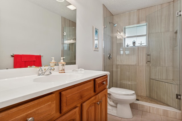 bathroom with tile patterned floors, vanity, a textured ceiling, a shower with door, and toilet