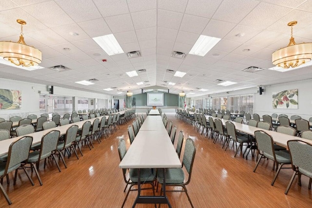 dining room featuring light wood-type flooring, a paneled ceiling, an inviting chandelier, and plenty of natural light