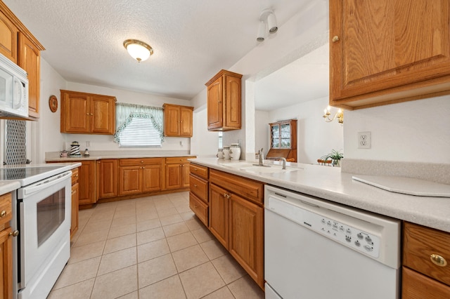 kitchen with white appliances, sink, light tile patterned floors, a textured ceiling, and kitchen peninsula