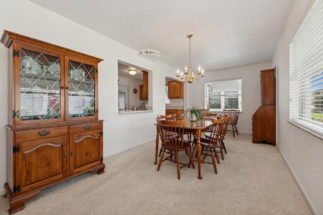 carpeted dining room with a chandelier and a textured ceiling