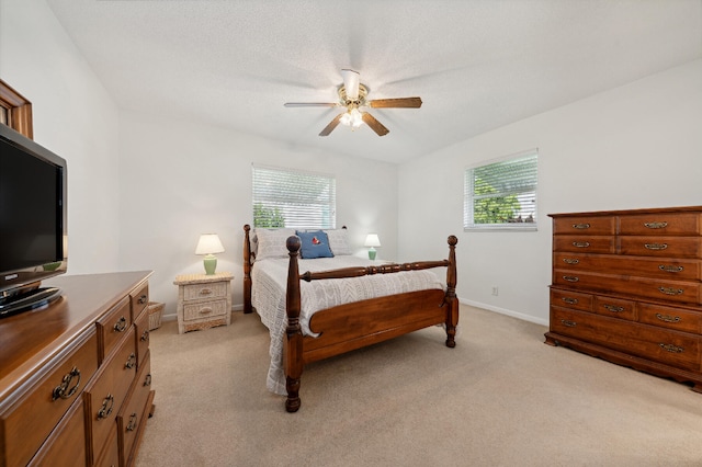 carpeted bedroom featuring ceiling fan, a textured ceiling, and multiple windows