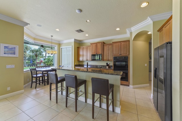 2233 SW Golden Bear Way, Palm City, FL 34990 - kitchen with black appliances, brown cabinetry, a breakfast bar area, arched walkways, and a center island with sink