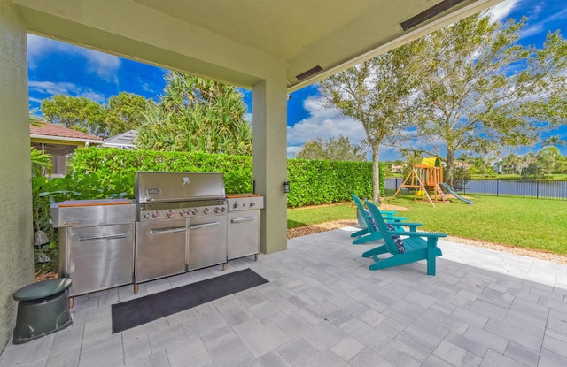 2233 SW Golden Bear Way, Palm City, FL 34990 - view of patio featuring exterior kitchen, a playground, and a water view