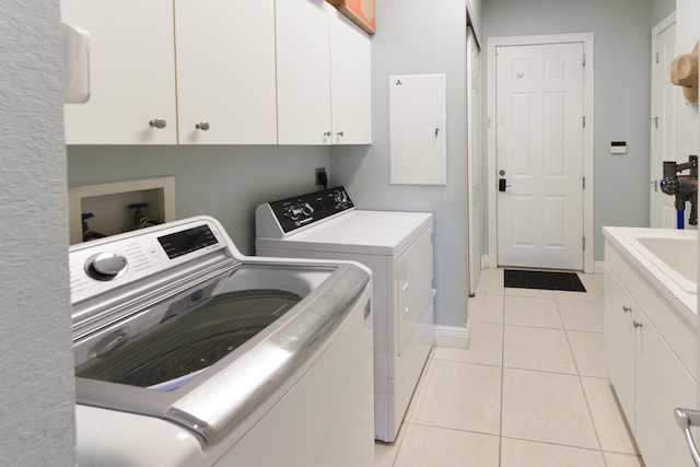 2233 SW Golden Bear Way, Palm City, FL 34990 - laundry area with washing machine and clothes dryer, cabinet space, light tile patterned floors, and baseboards
