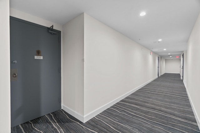 corridor featuring dark colored carpet and a barn door