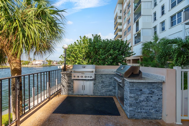 view of patio with an outdoor kitchen, a grill, and a water view