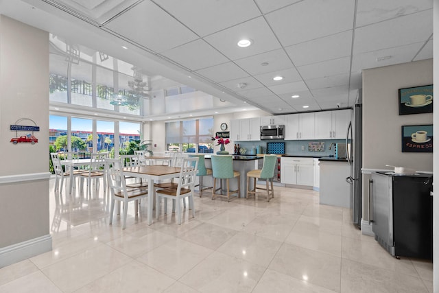 tiled dining space featuring a paneled ceiling and sink