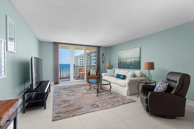 living room featuring light tile patterned floors, a textured ceiling, and a wall of windows