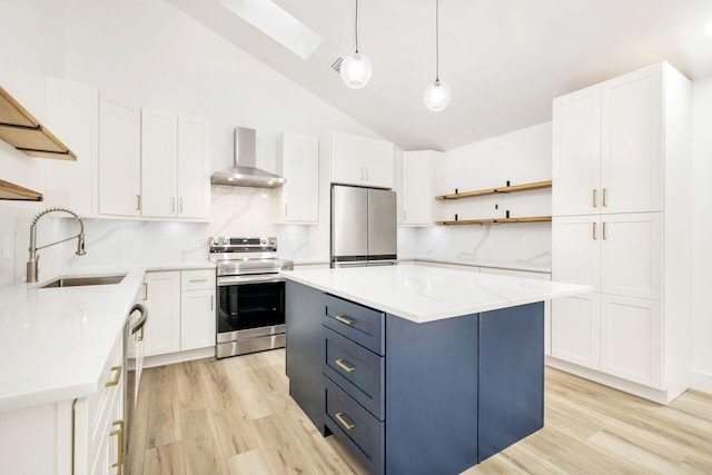 kitchen featuring white cabinetry, wall chimney exhaust hood, hanging light fixtures, vaulted ceiling with skylight, and appliances with stainless steel finishes