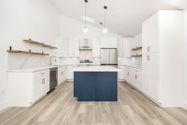 kitchen with stainless steel appliances, wall chimney range hood, high vaulted ceiling, white cabinets, and a center island